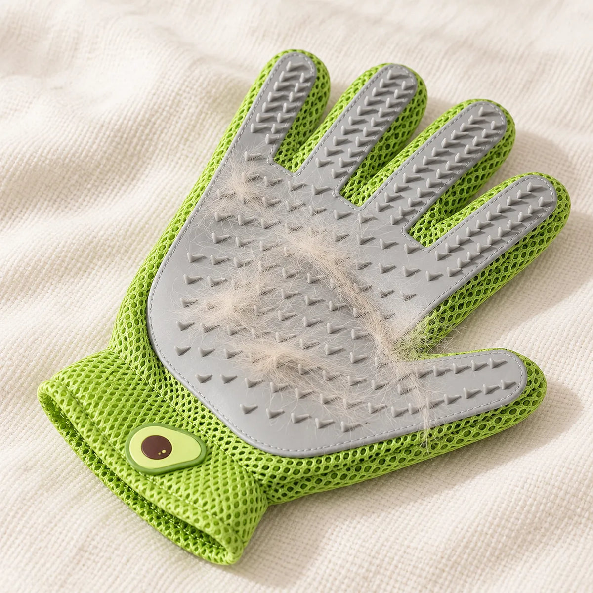 Green grooming glove holding loose fur lifted from a coat