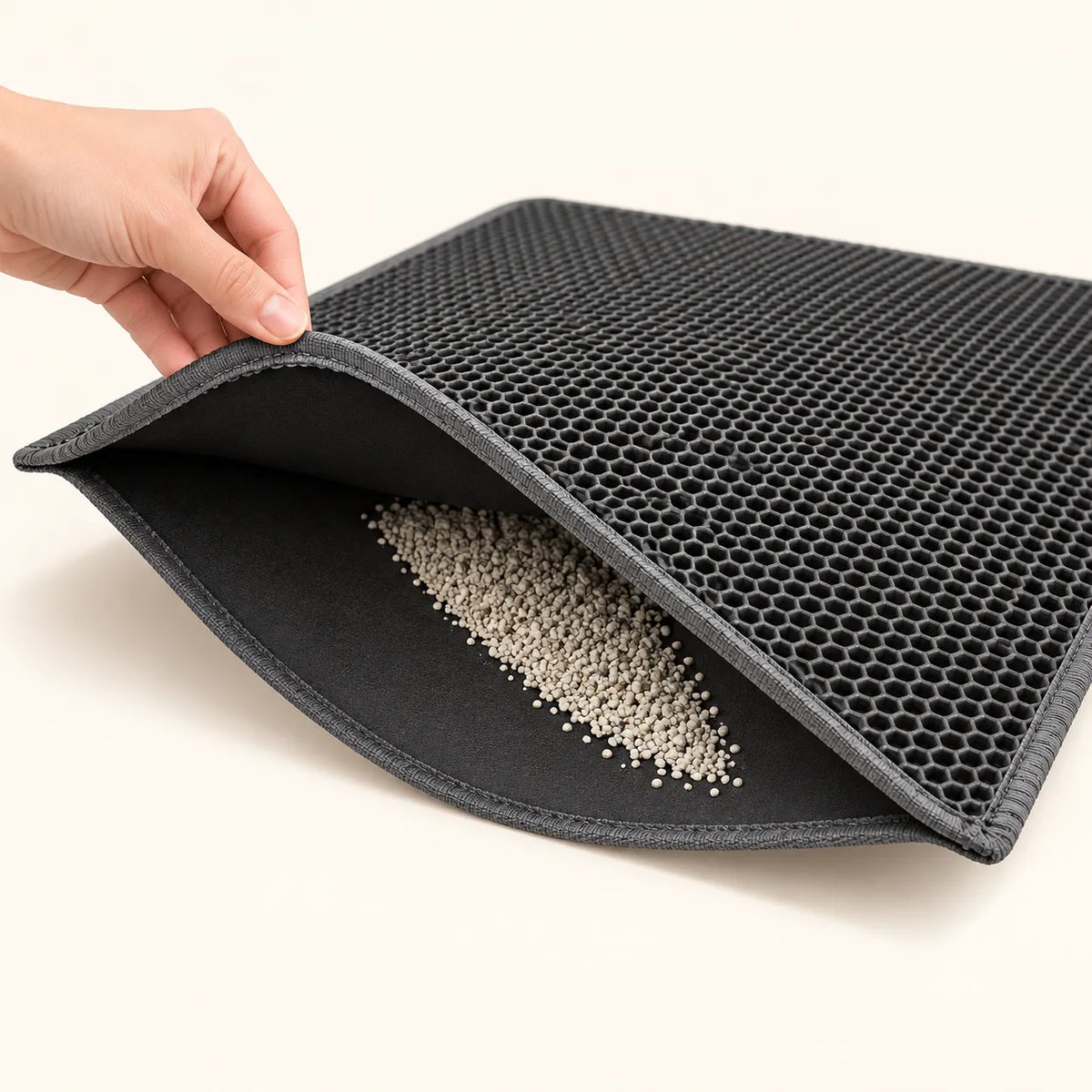 Opening the two layers of the Honeycomb Litter Mat to pour out collected litter