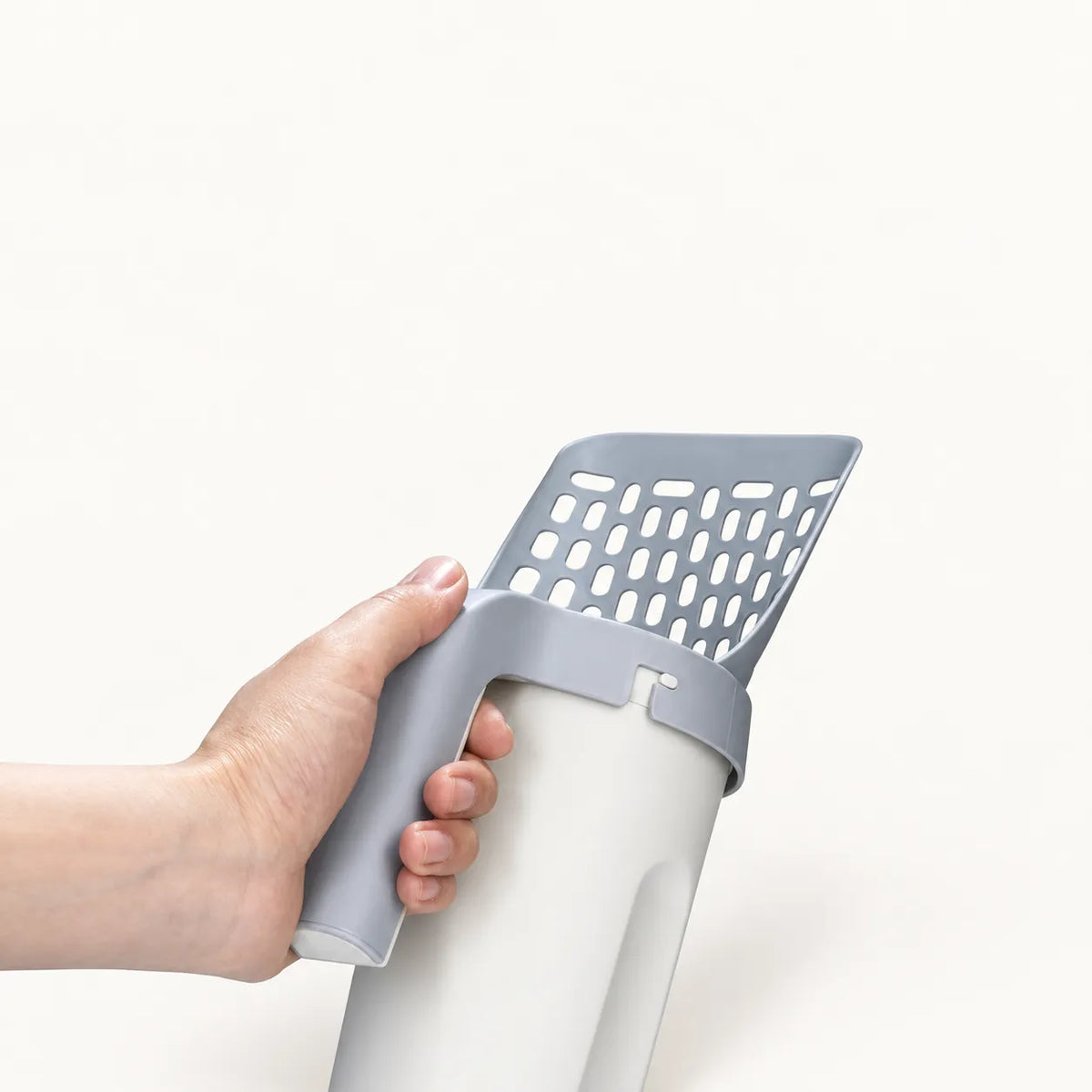 Hand lifting the litter scoop out of its storage base